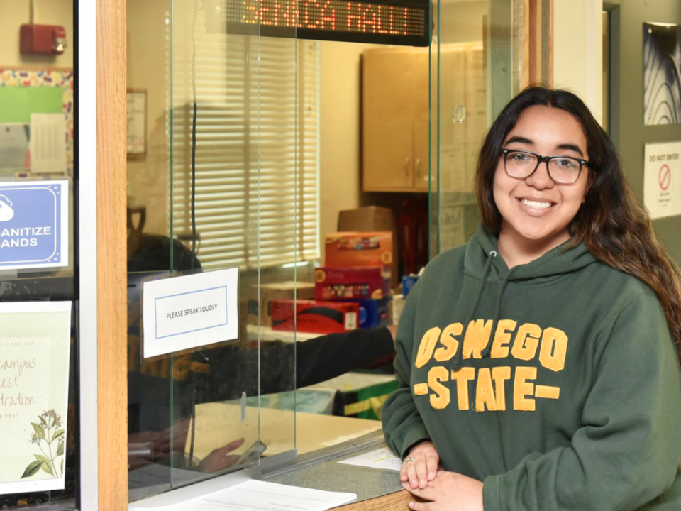 Student in front of Seneca Hall&#039;s front desk. 