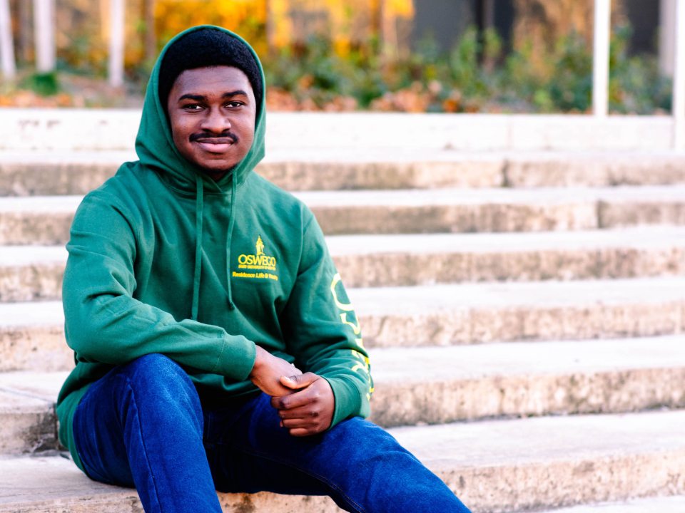 Student sitting on stairs wearing an RA hoodie. 