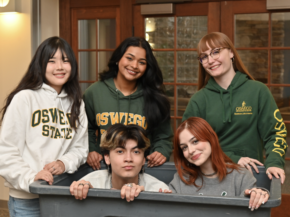 Students in Oswego hoodies in a moving bin.