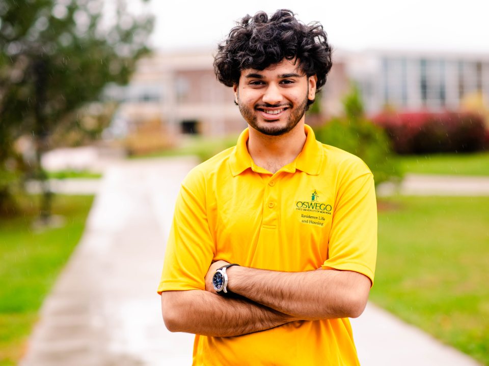 RA Puru smiling at the camera with crossed arms