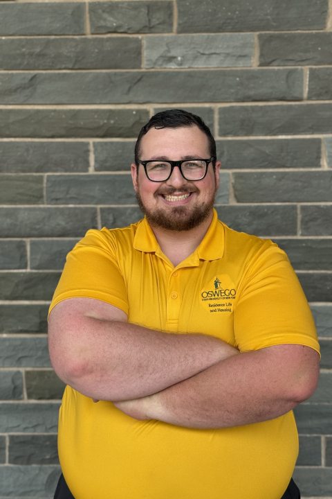 Garret Stauffer wearing a yellow t-shirt and smiling.
