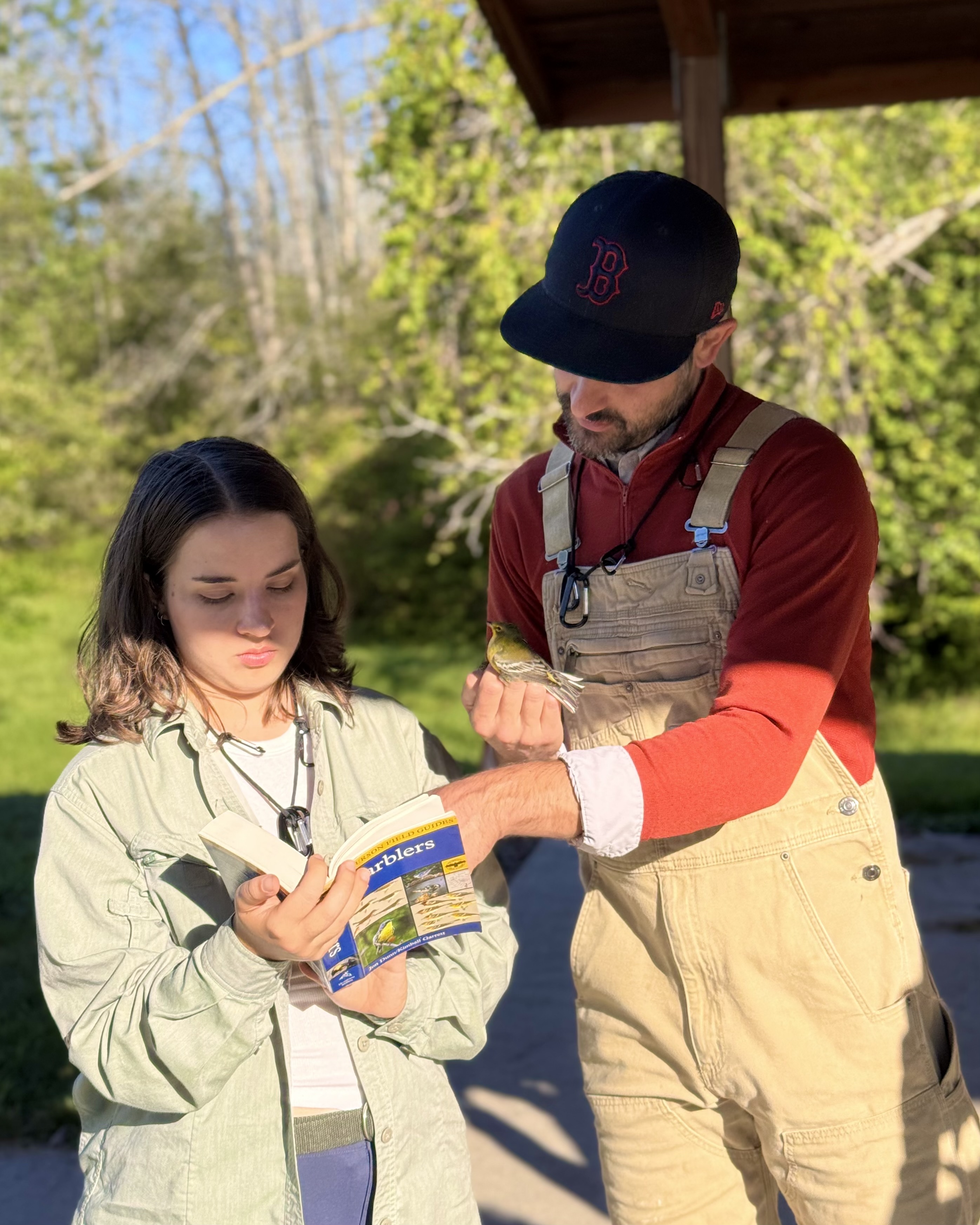 Two people consult a book while holding abird