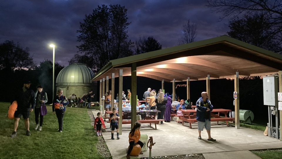 People gather at night in a pavilion wearing Halloween attire