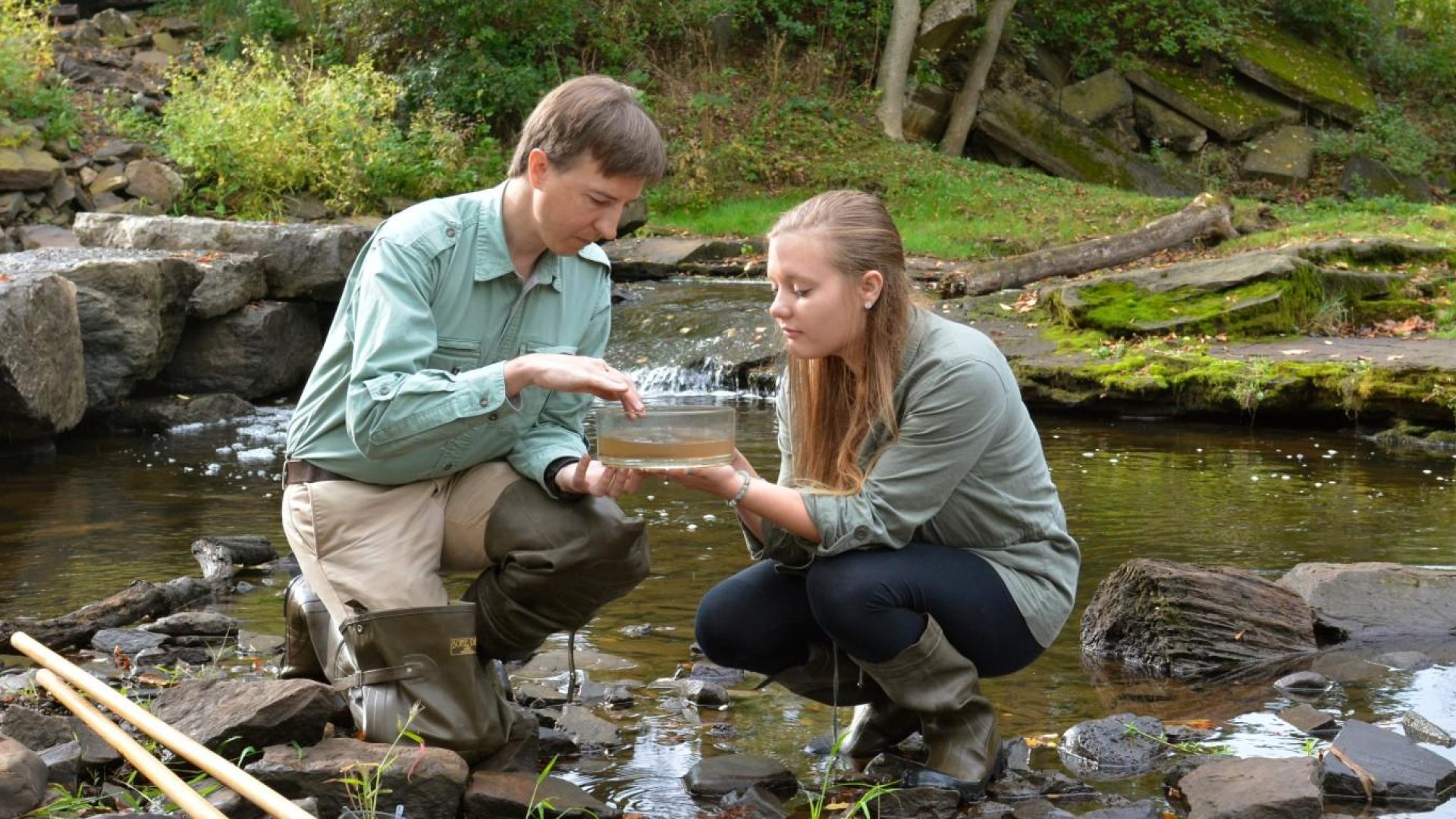 mentor and student in a stream looking a a stream sample