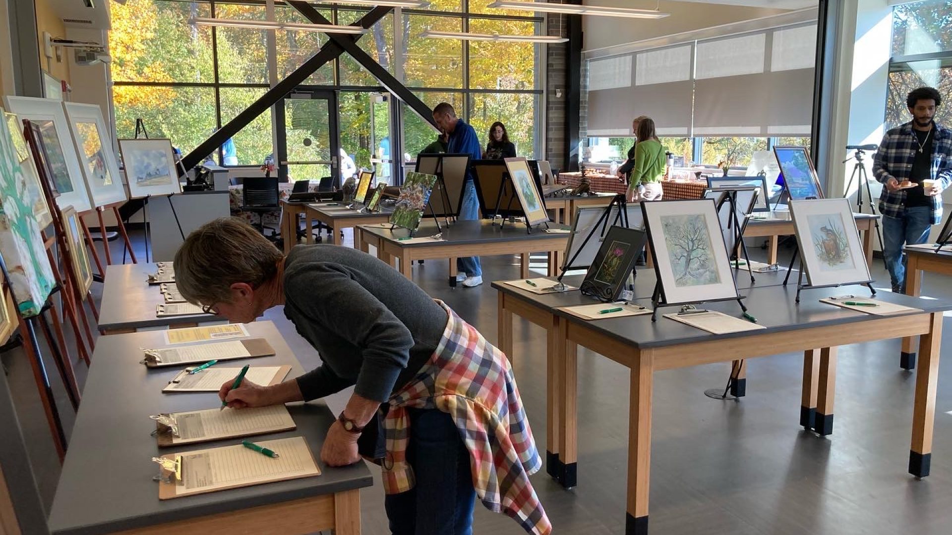 Someone makes a bid on a clipboard in a room where art is displayed