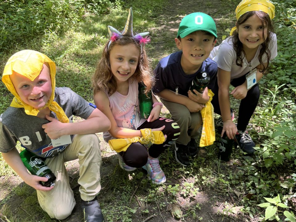 Kids squatting on a trail wearing yellow bandanas