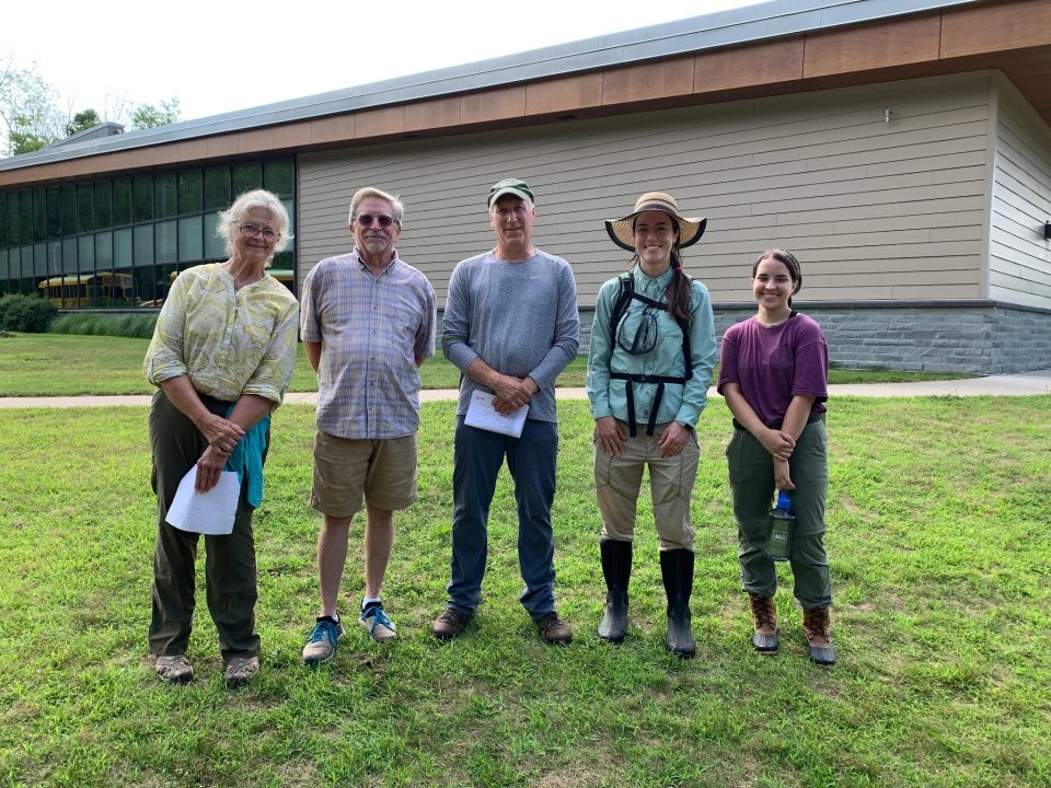 Five people pose in front of the building