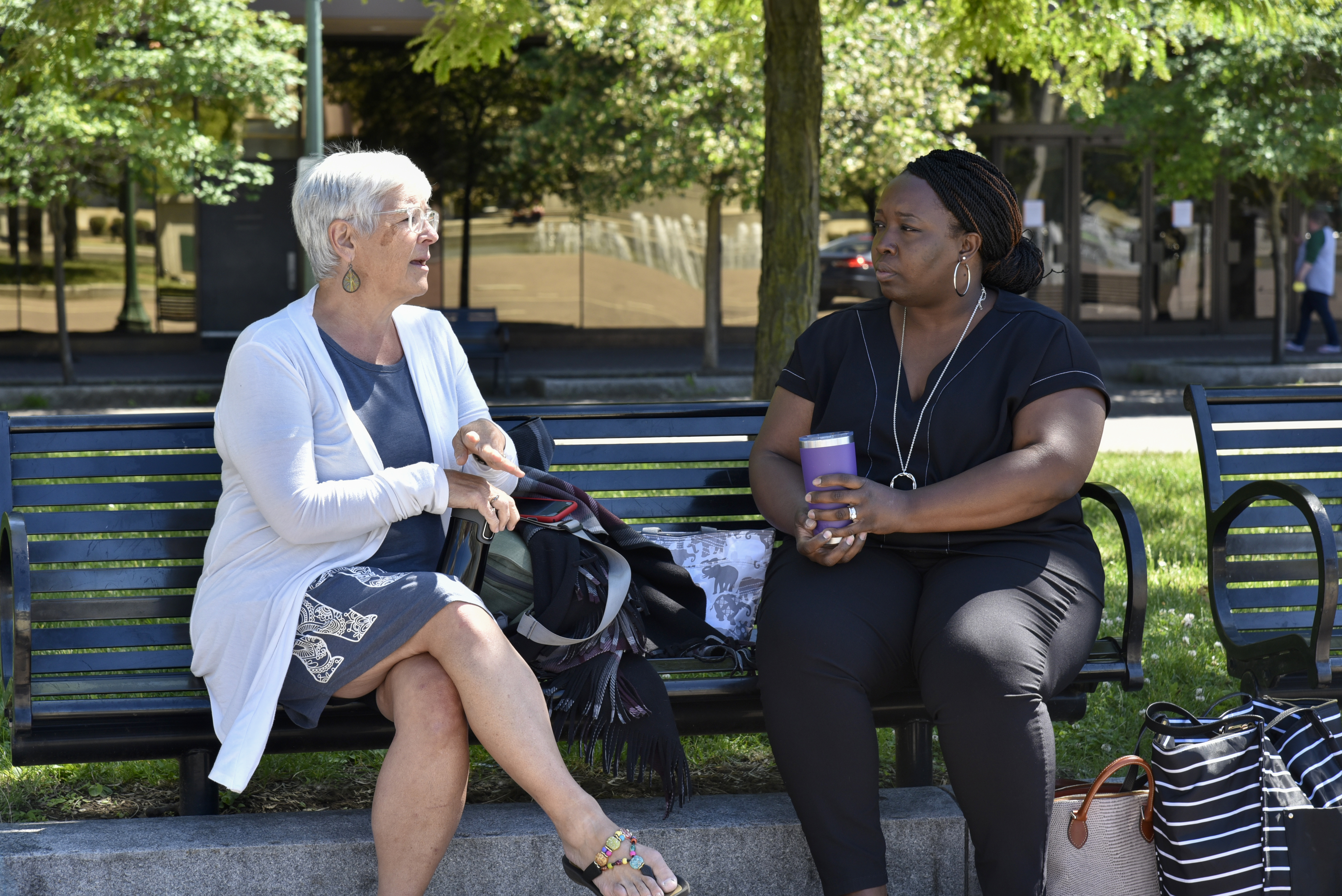 two women sitting on a park bench talking