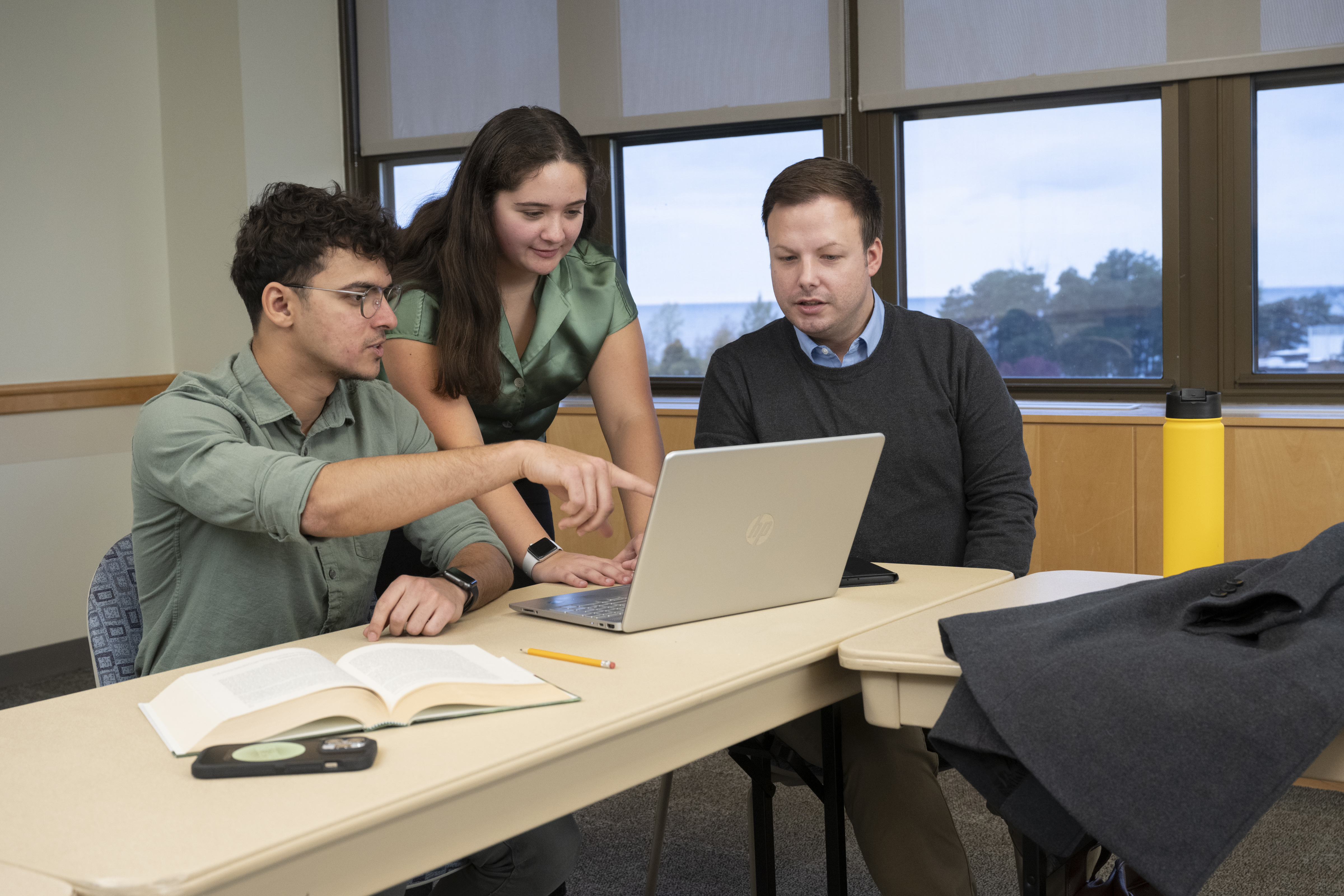 three students working on a laptop