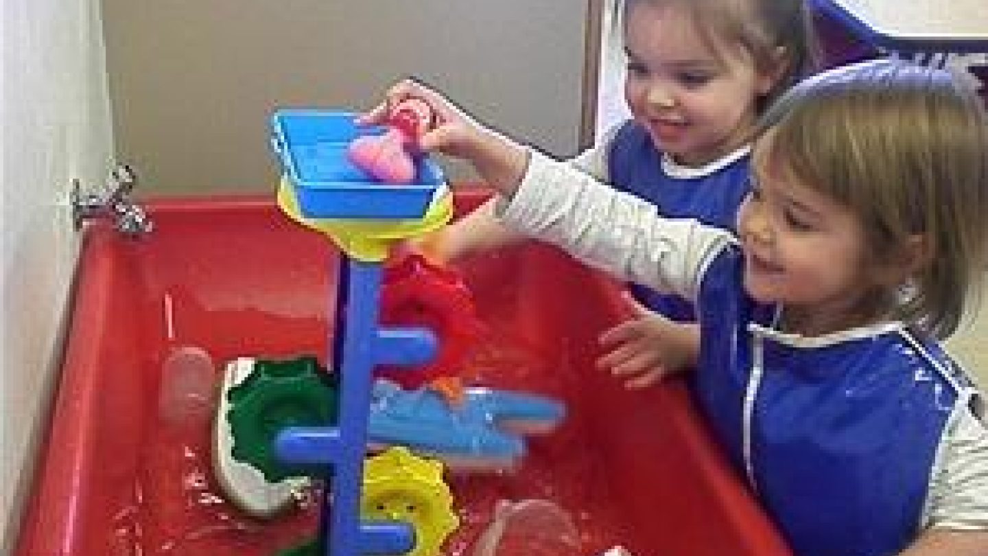 Two young children playing at a water table