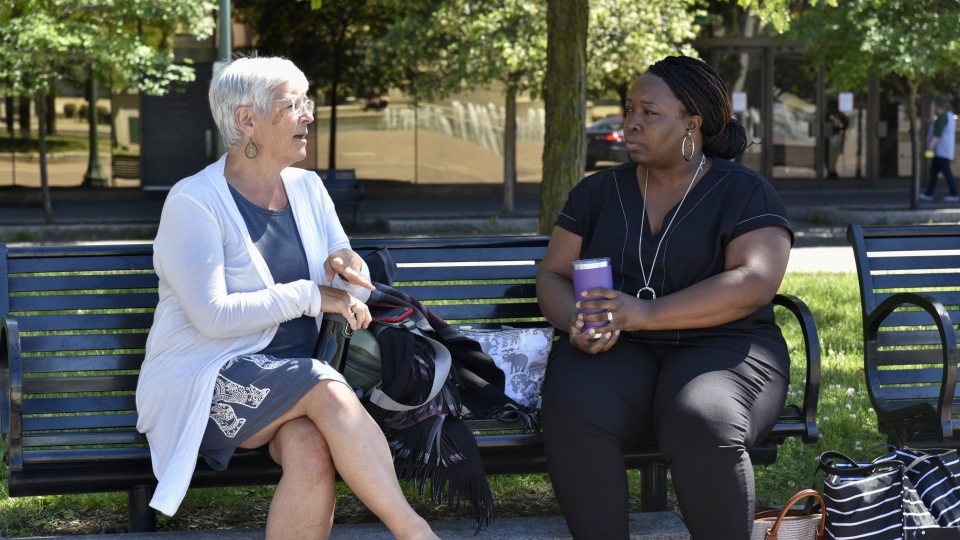 two women sitting on a park bench talking