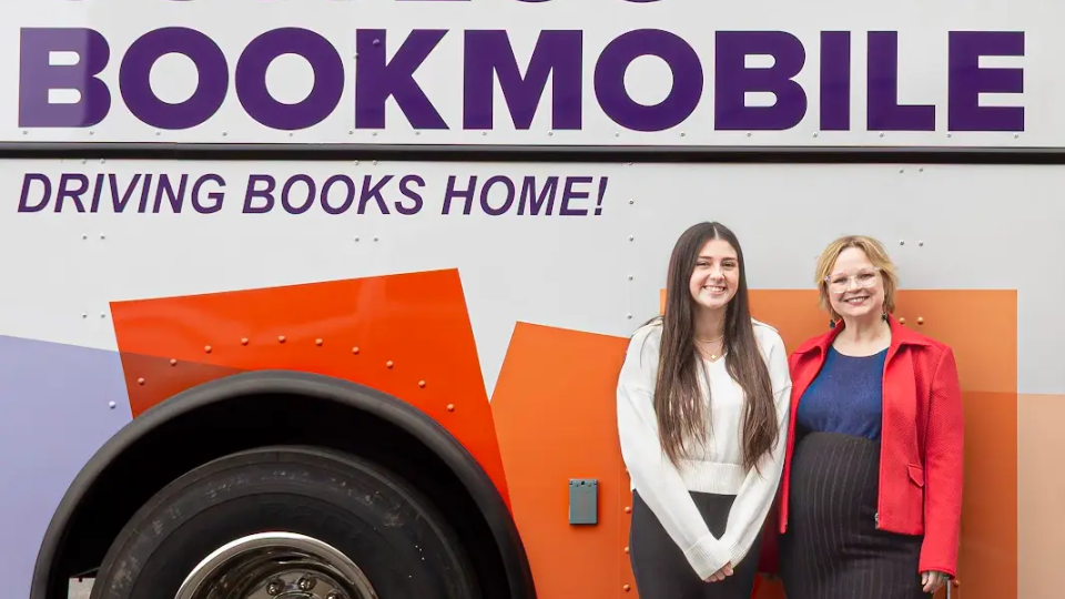 Hope Juratovac standing with another person in front of the Oswego Bookmobile.