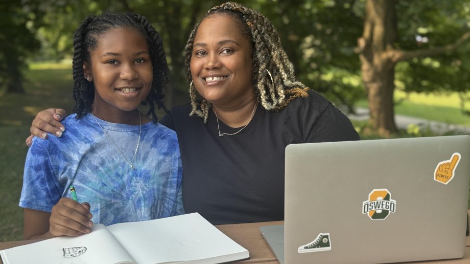 adult learner and her daughter smiling at a table doing school work together