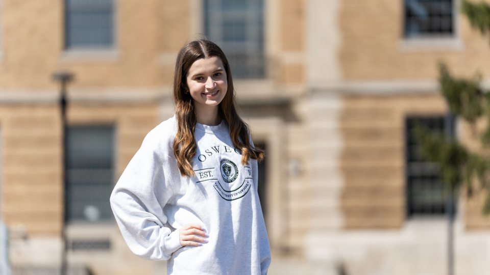 SUNY Oswego Happy Student in front of Rick Hall 