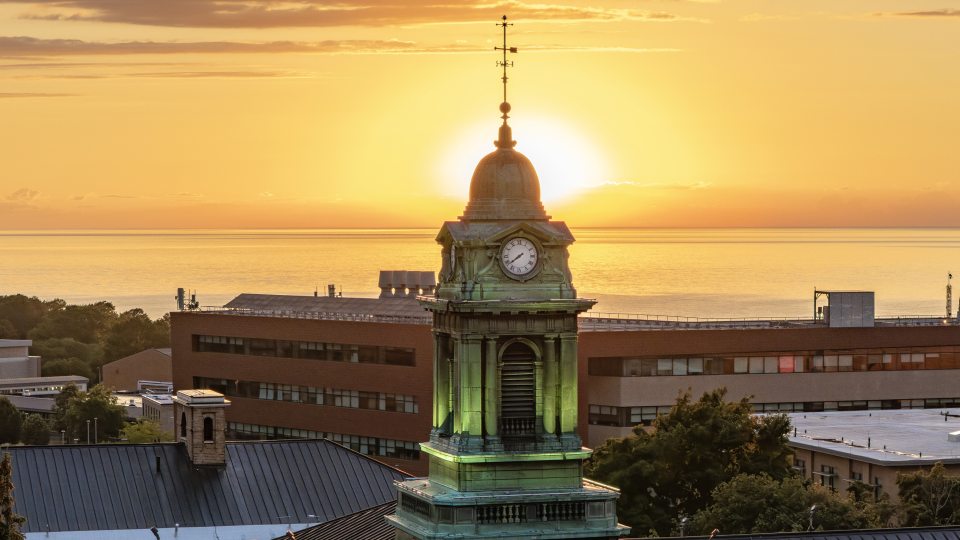 picrture of sheldon hall with a golden sunset behind it 