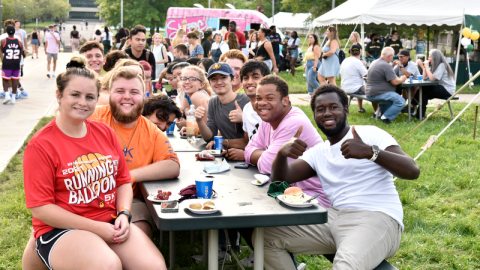 A group of students at a picnic table. One student gives double thumbs up.