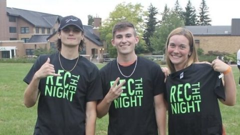 Three students wearing black t-shirts with green wording "Rec the Night"