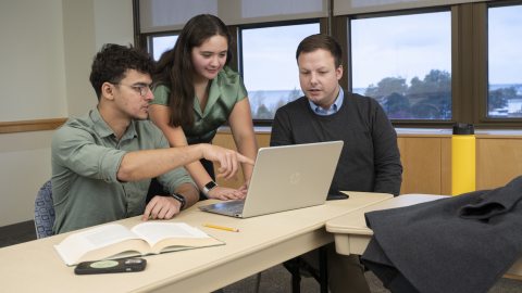 three students working on a laptop