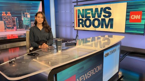 SUNY Oswego broadcasting student Clarissa Karki, sitting at the news desk at CNN headquarters in Atlanta during a summer internship, won multiple Broadcast Education Association awards.