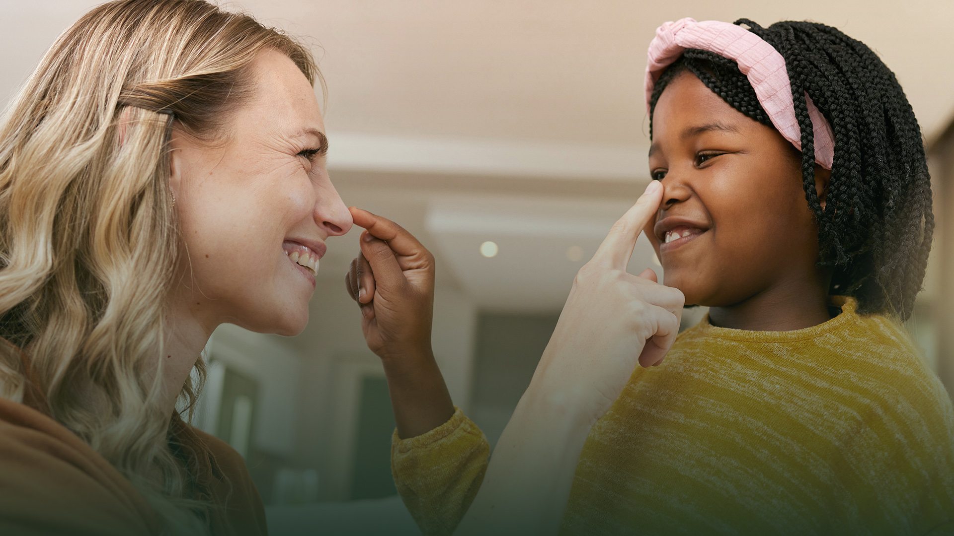 A woman and girl playfully touch each other’s noses.