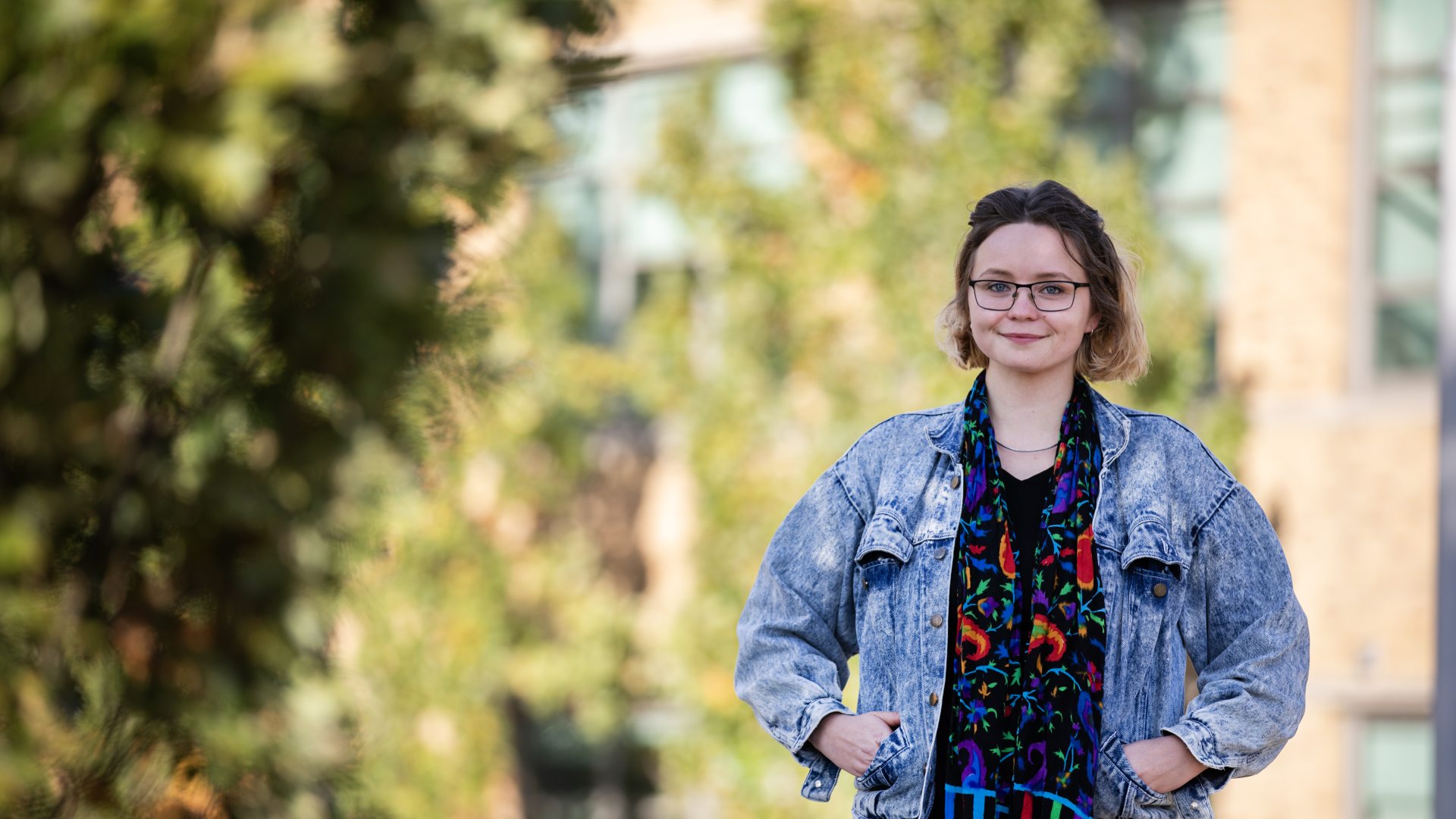 A SUNY Oswego at Syracuse student stands outdoors in downtown Syracuse near campus, smiling toward the camera.
