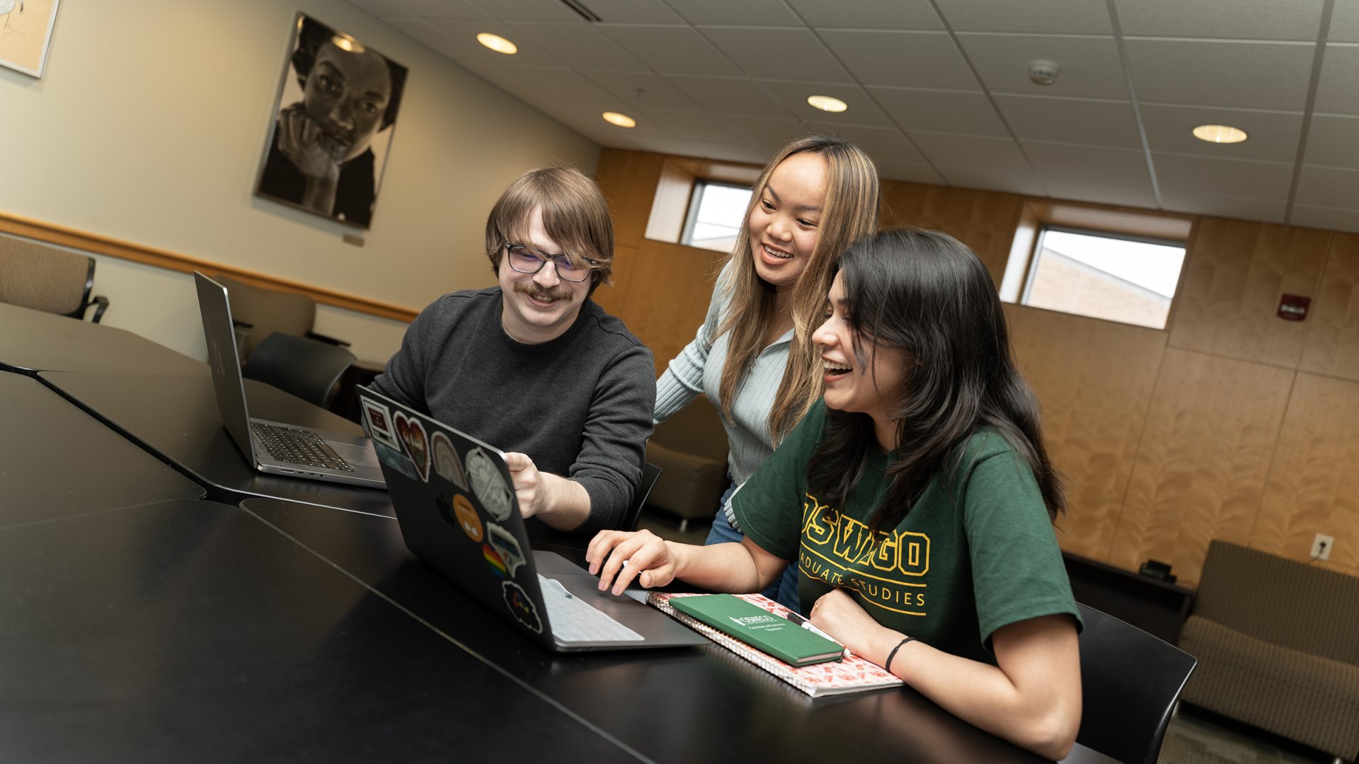 Three students collaborating around laptops.