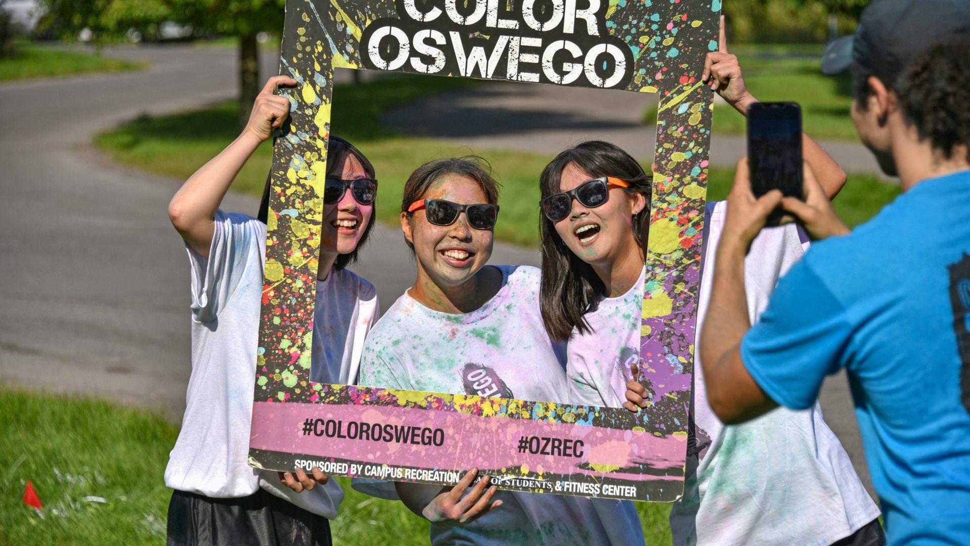 Three students pose for a photo after the Oswego Color Run