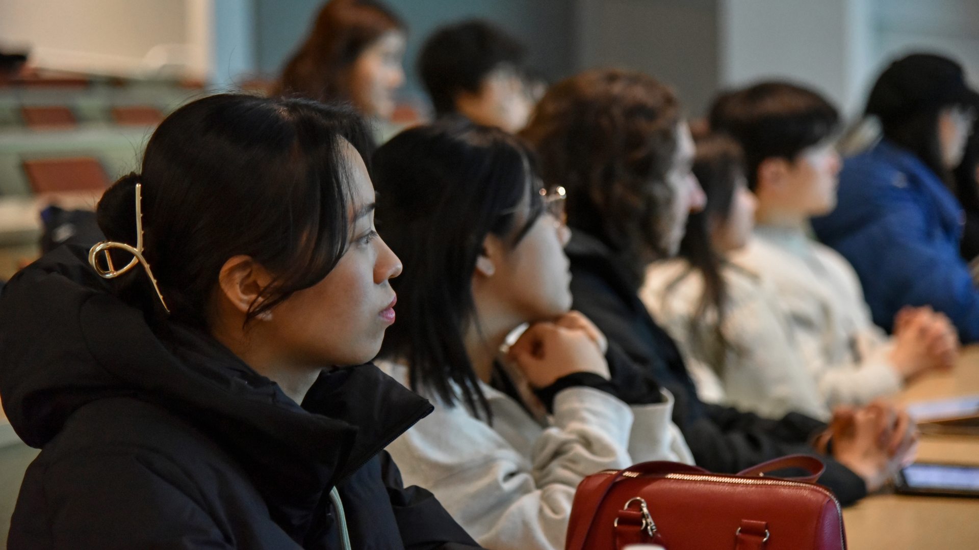 International students listen attentively during an orientation session in a campus classroom, participating in a group presentation as they begin their academic journey at SUNY Oswego.