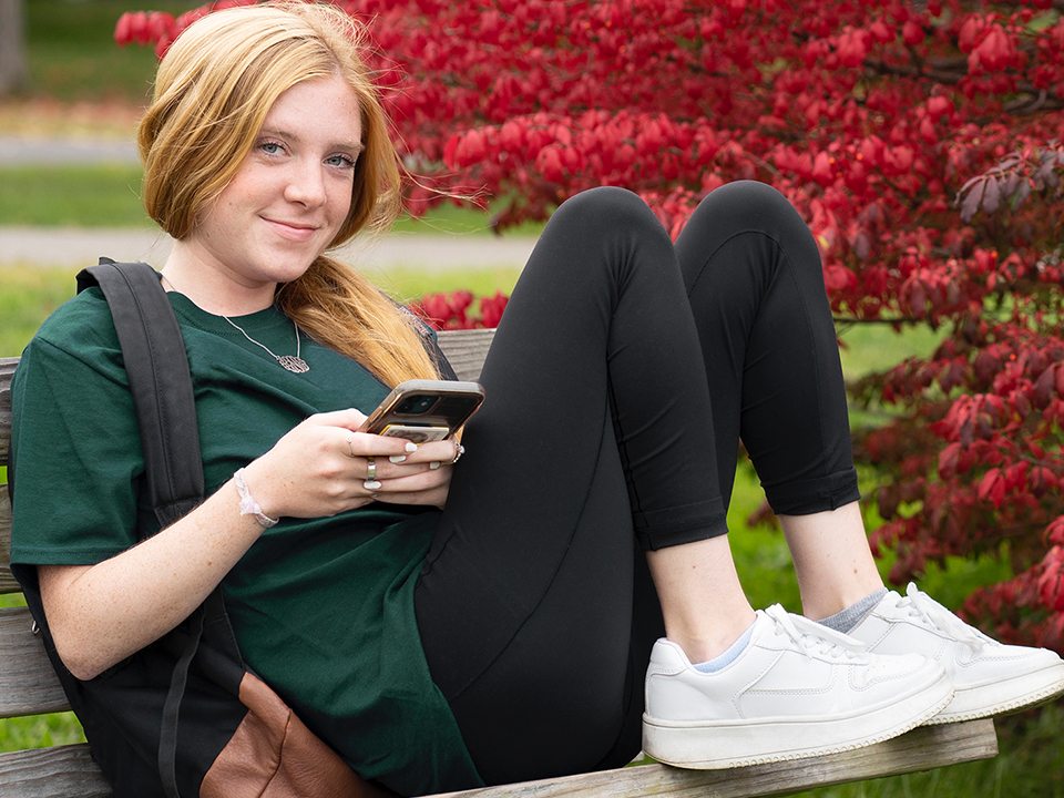 An Oswego students texts a friend during a break at glimmerglass lagoon.