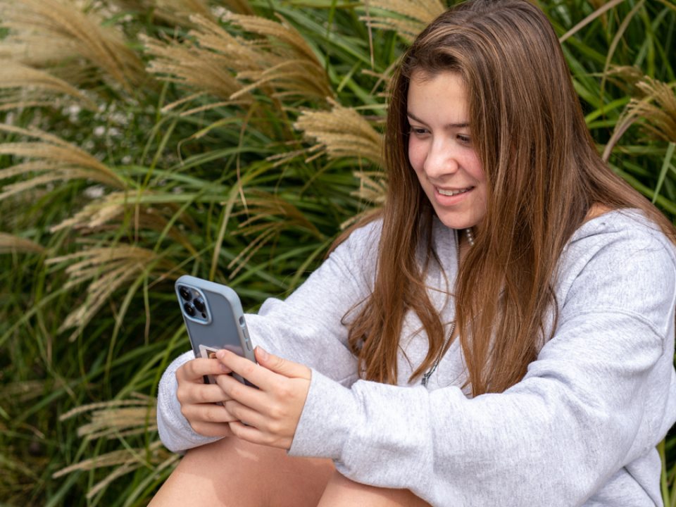 A young woman sits texting