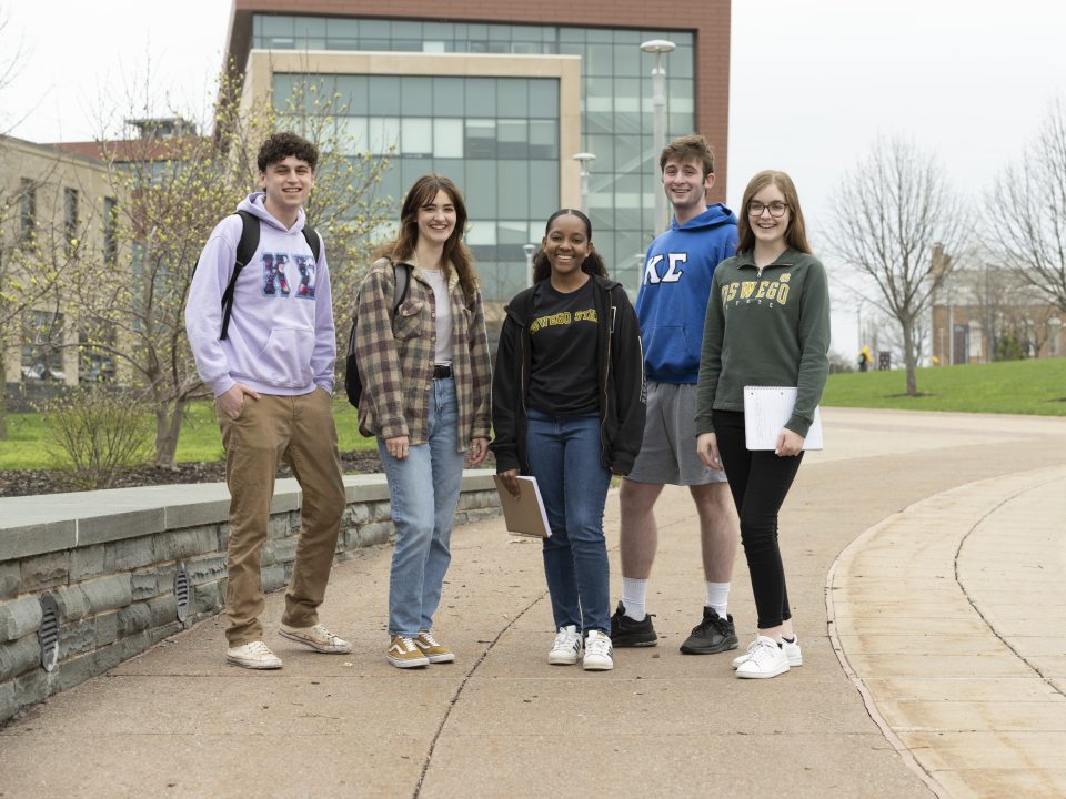 Five students standing on the pathway outside of Marano Campus Center