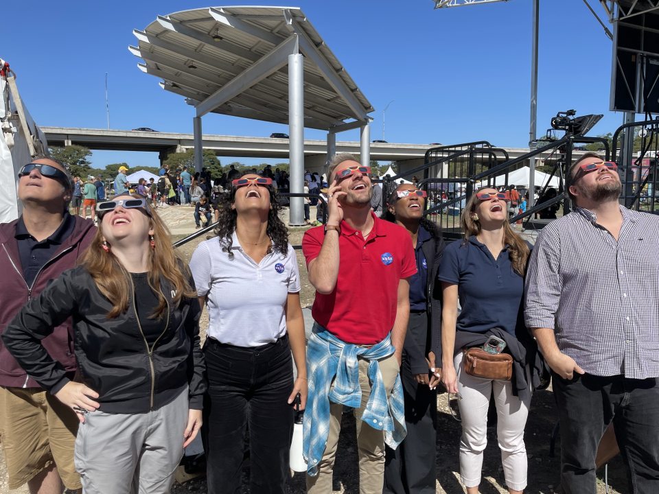 A group of people wearing protective glasses as they view an eclipse