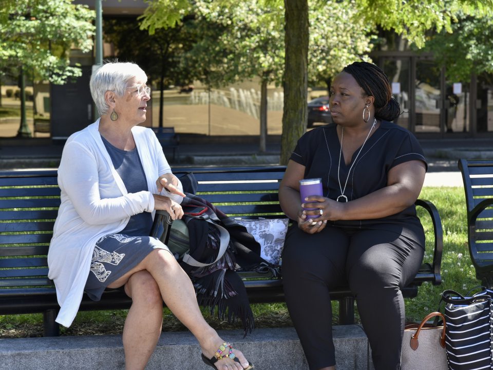 two women sitting on a park bench talking