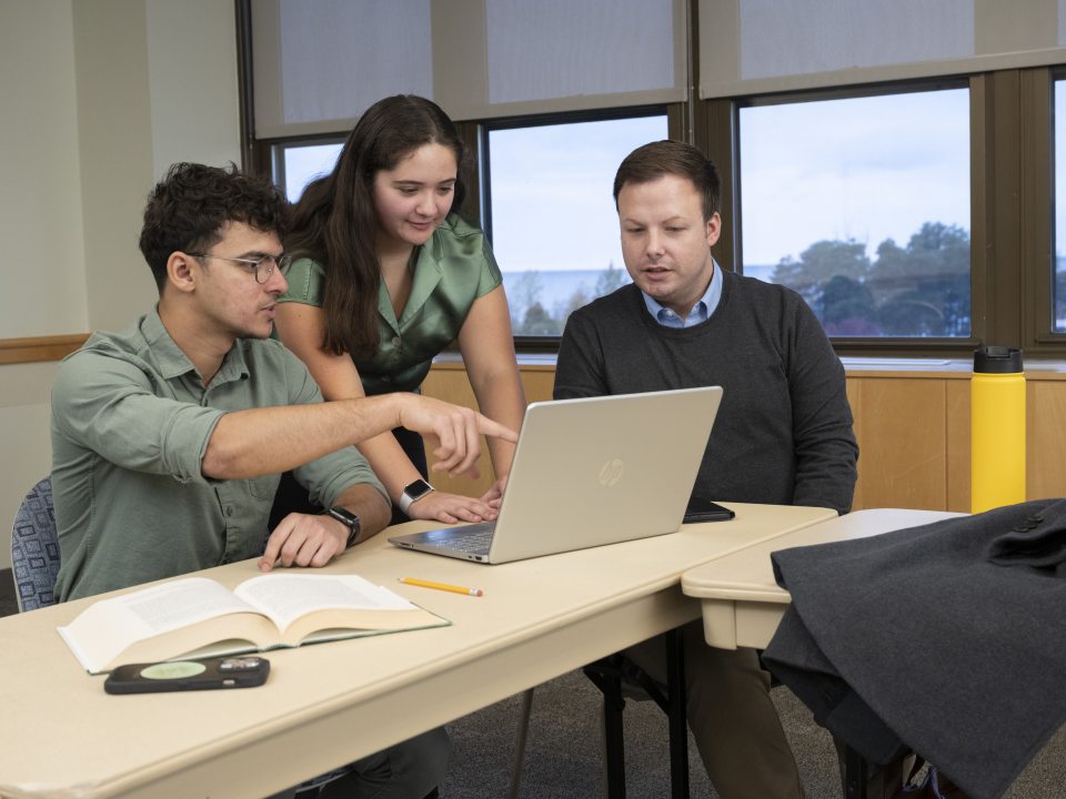 three students working on a laptop