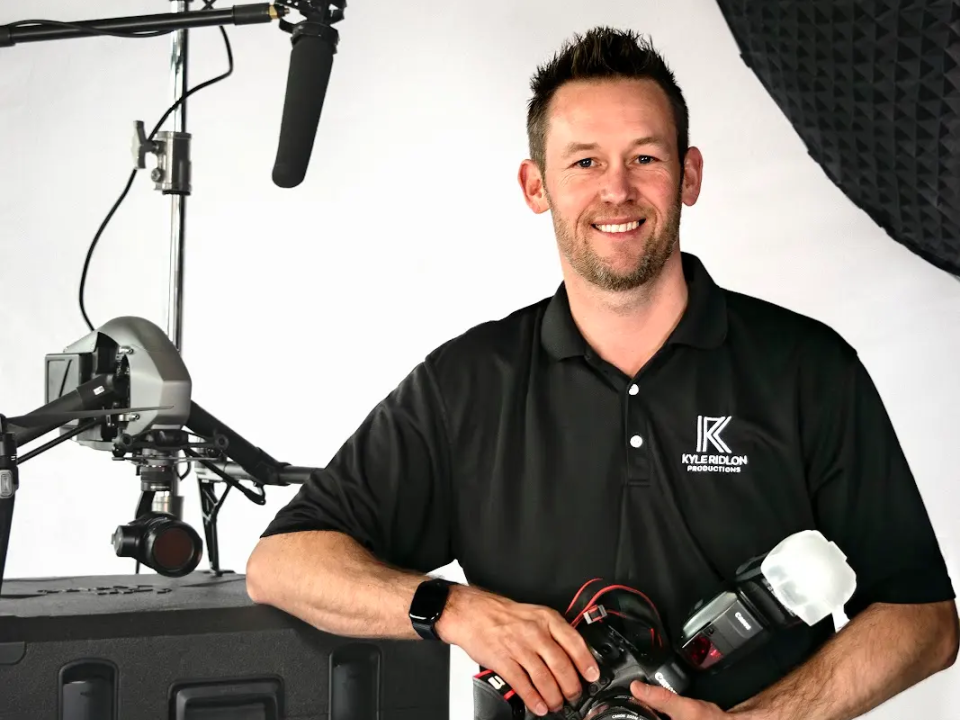 Kyle Ridlon holding a camera in a photography studio.