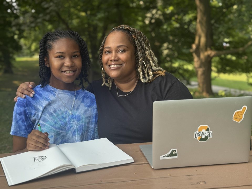 adult learner and her daughter smiling at a table doing school work together