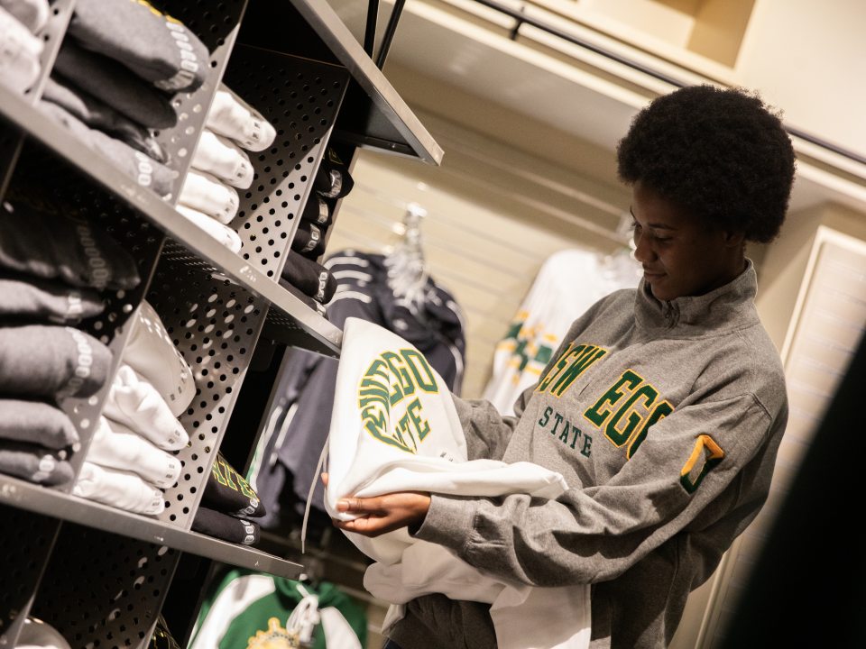 SUNY Oswego student looking at Oswego gear at the college bookstore