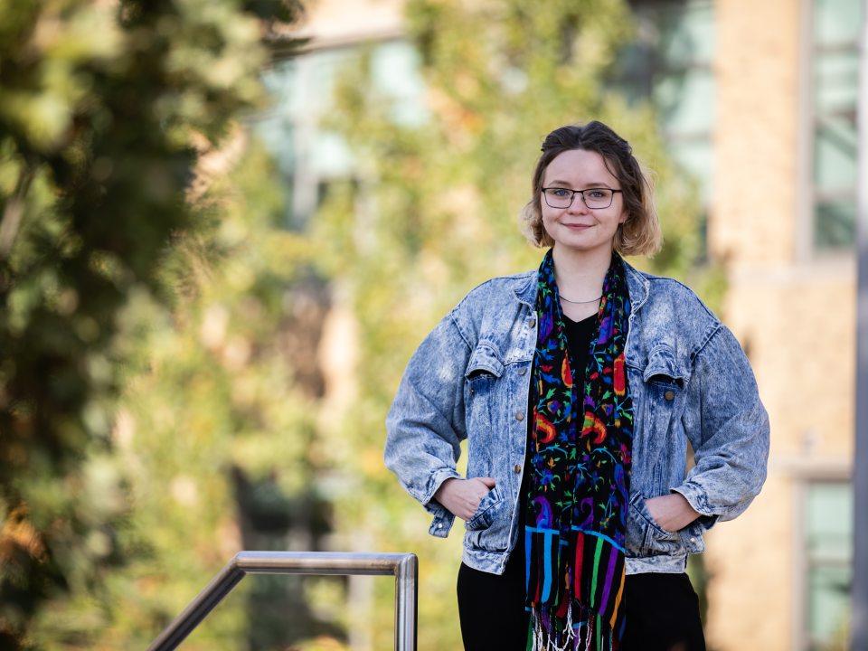 A SUNY Oswego at Syracuse student stands outdoors in downtown Syracuse near campus, smiling toward the camera.