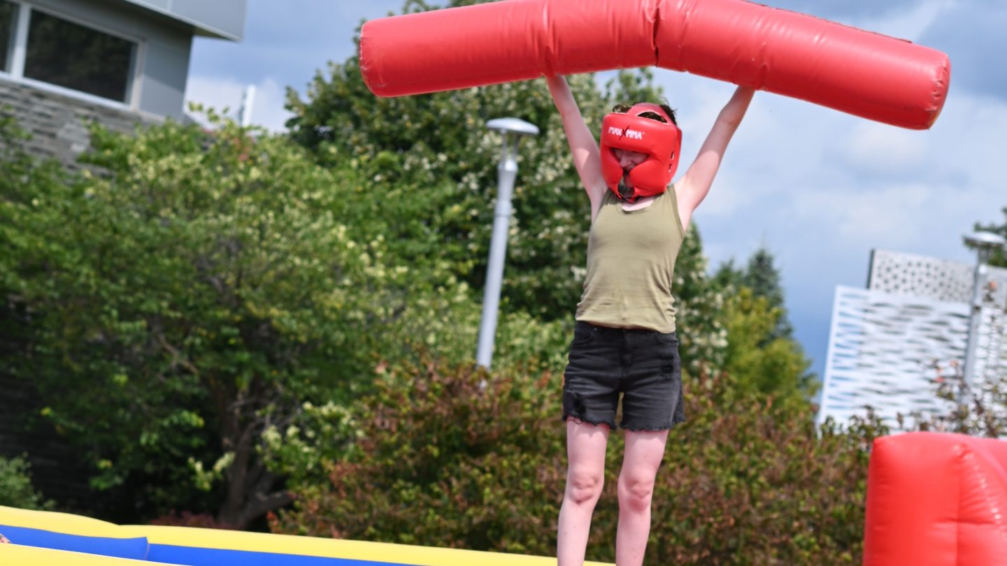 Student holding up foam jousting tube in victory