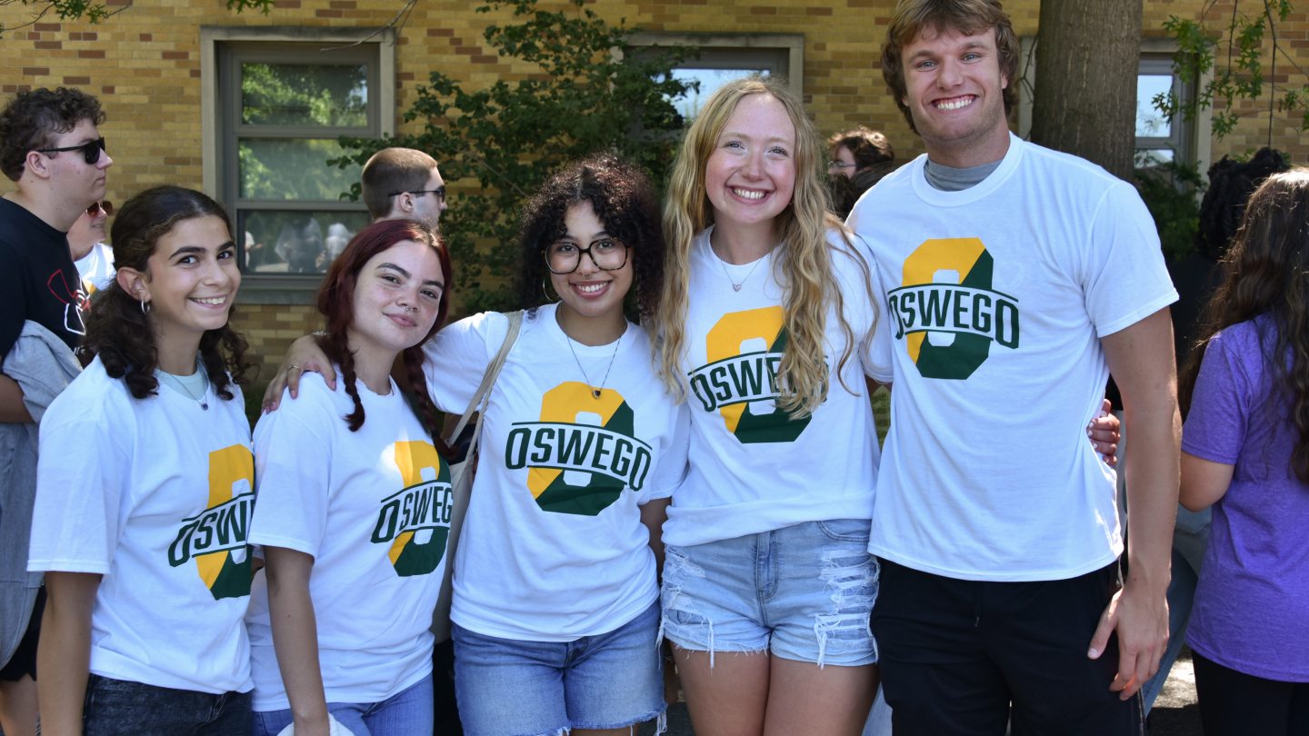 Students in matching Oswego O shirts smiling into the camera
