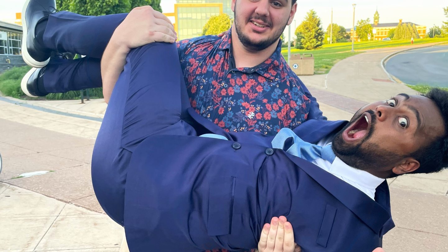 One Laker Leader carrying another Laker Leader, both making a goofy face toward the camera