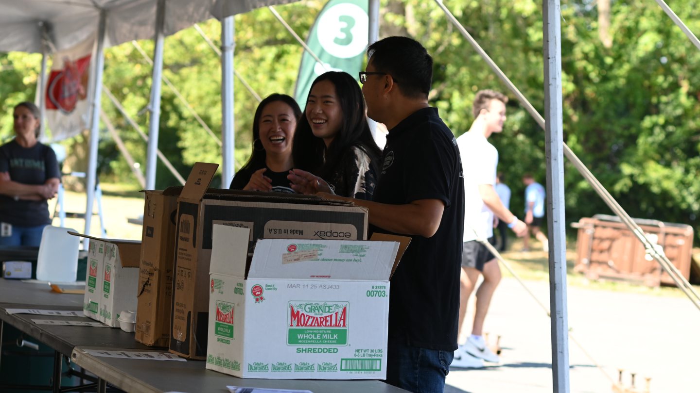 Three people laughing over open boxes of food