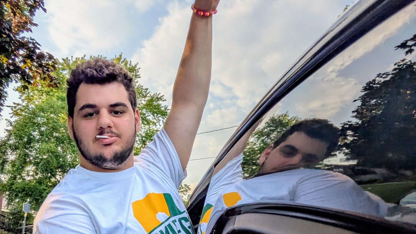 Orientation Leader standing out of a van, pointing to the sky.