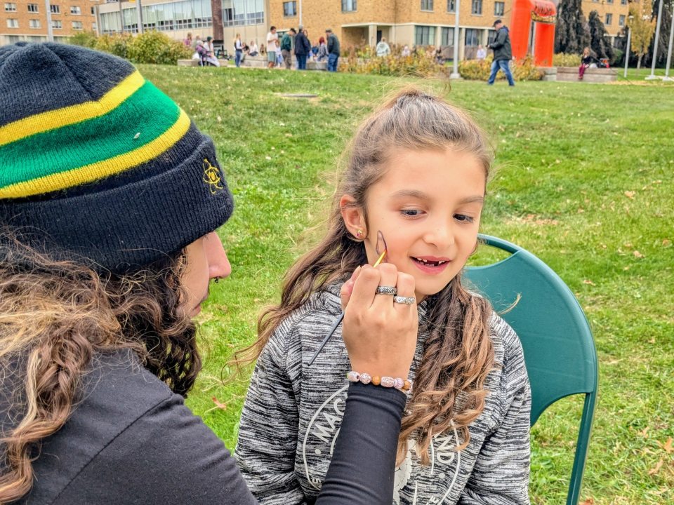Student Staff worker face paints with a younger family member