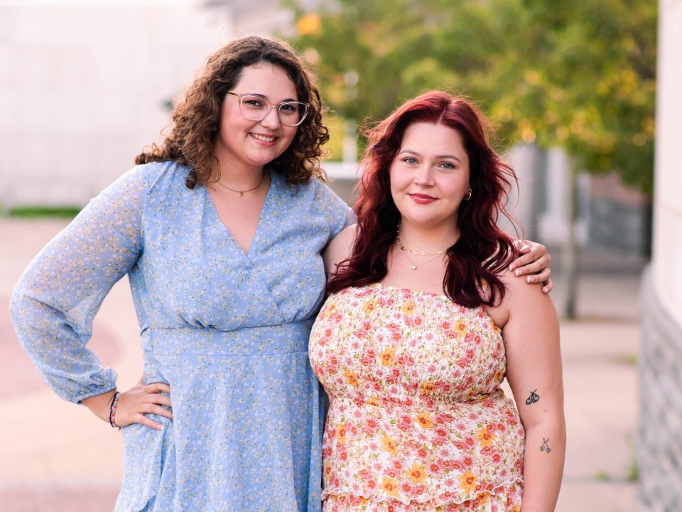 Two members of office staff smiling towards the camera