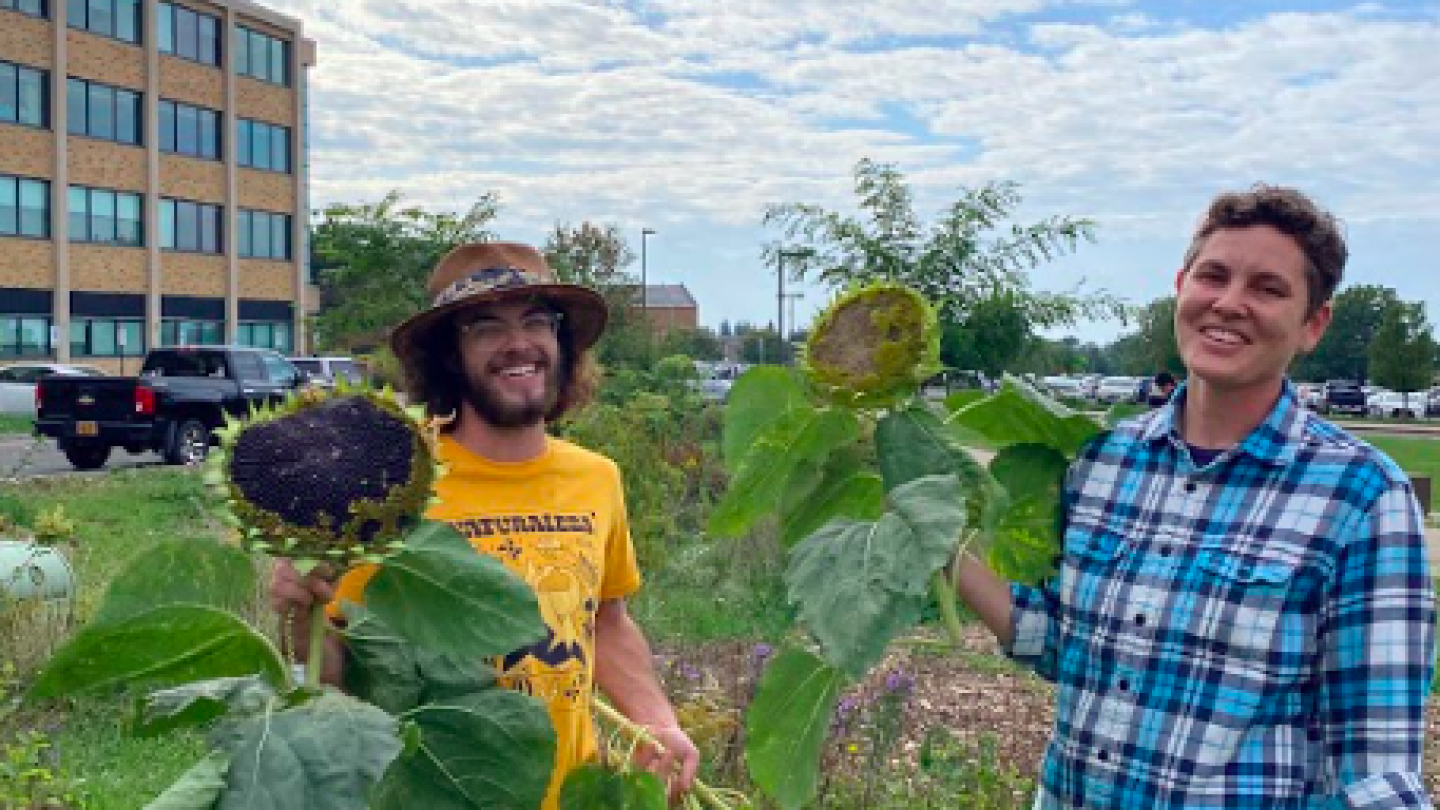 Two people holding large sunflowers