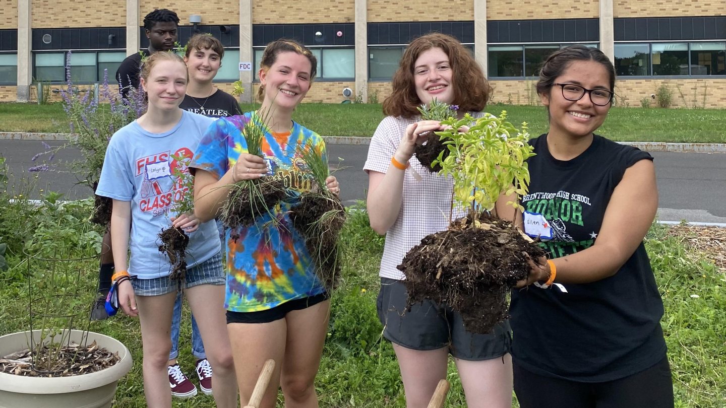 A group of students holding plants from the PLL garden