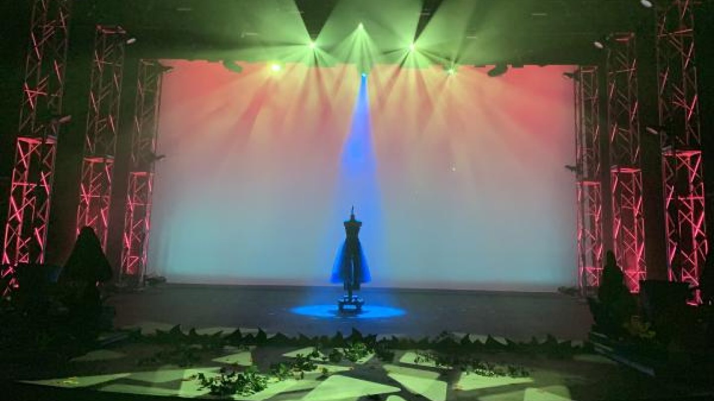 A dress on a stand, center stage under green lights
