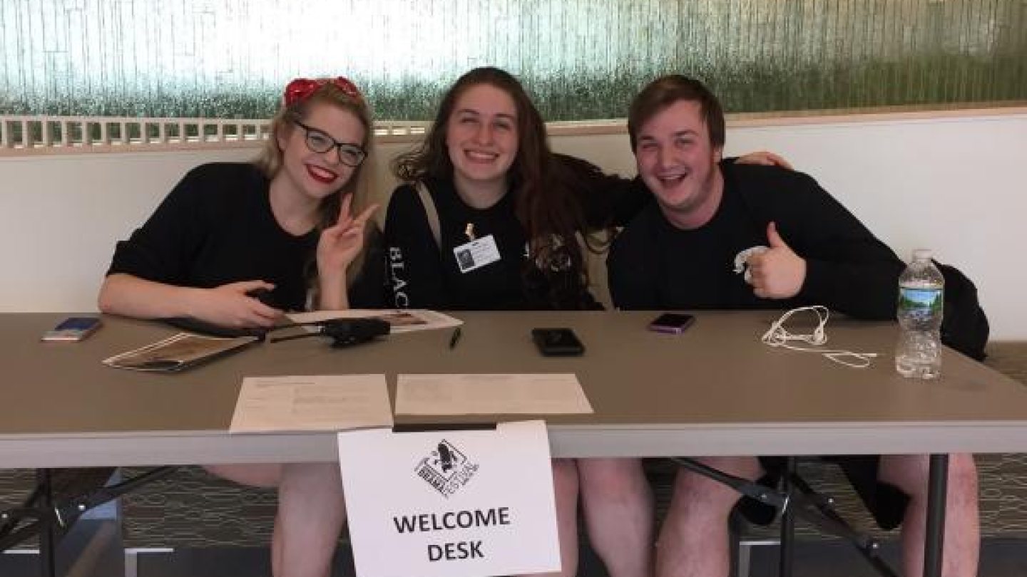 Three students sitting at a welcome table