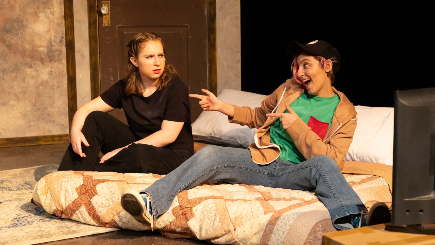 Two people sitting on a mattress on the floor